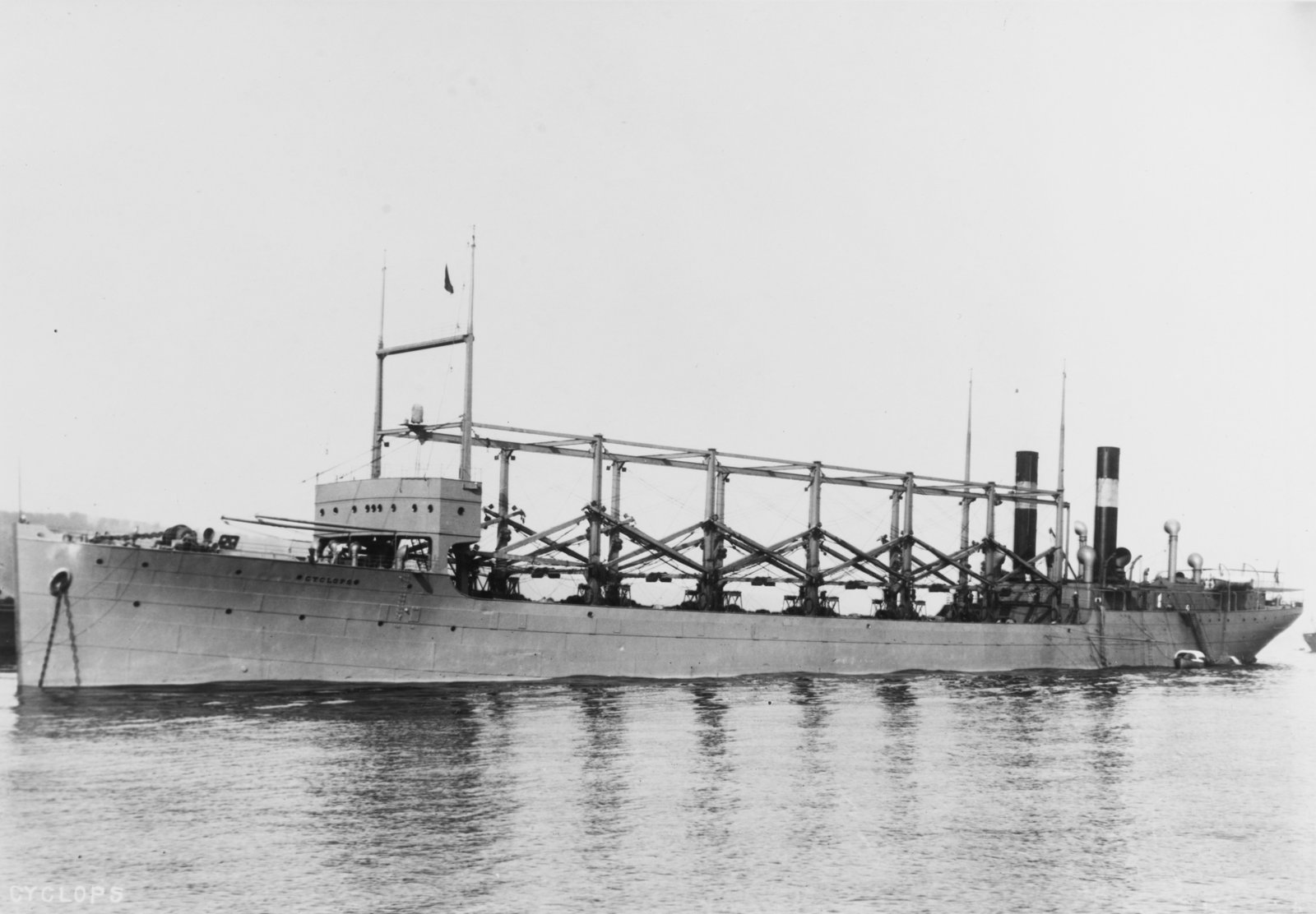 USS Cyclops underway, a large collier with tall cargo-handling booms along her deck